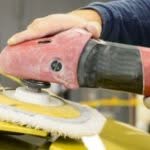 carrozziere che passa attrezzo per lucidatura su carrozzeria auto