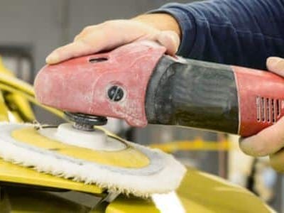 carrozziere che passa attrezzo per lucidatura su carrozzeria auto