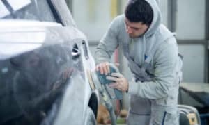 carrozziere che svernicia auto per riparazione